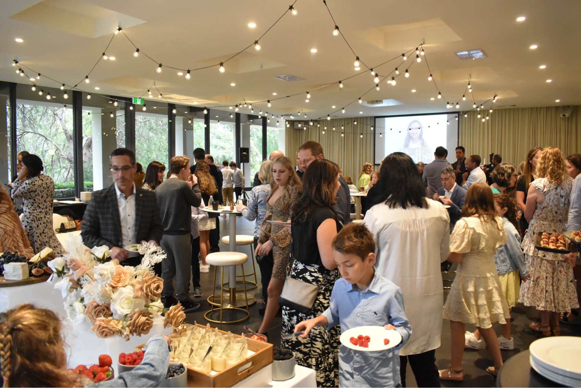 A bustling crowd gathers around a lavish buffet table at Leonda by the Yarra. Food galore and happy faces!