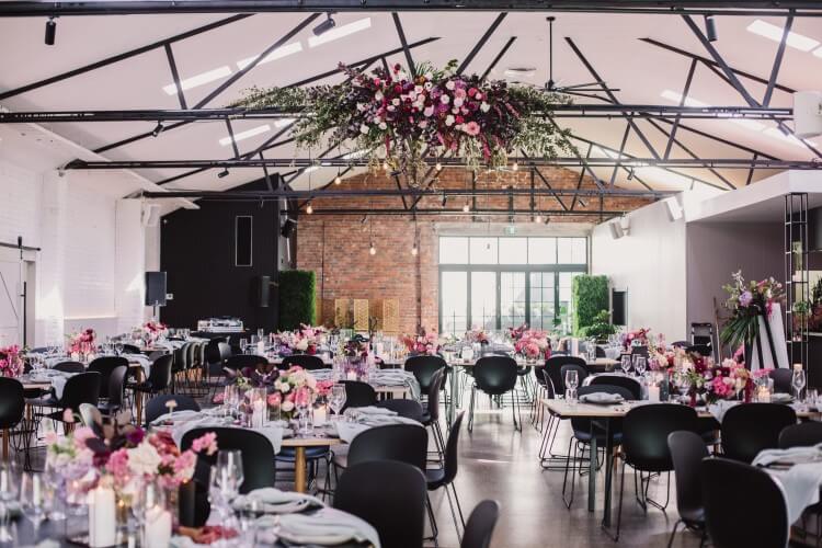 An intimate wedding reception with flickering candles and lush green plants, set in a Melbourne warehouse venue.