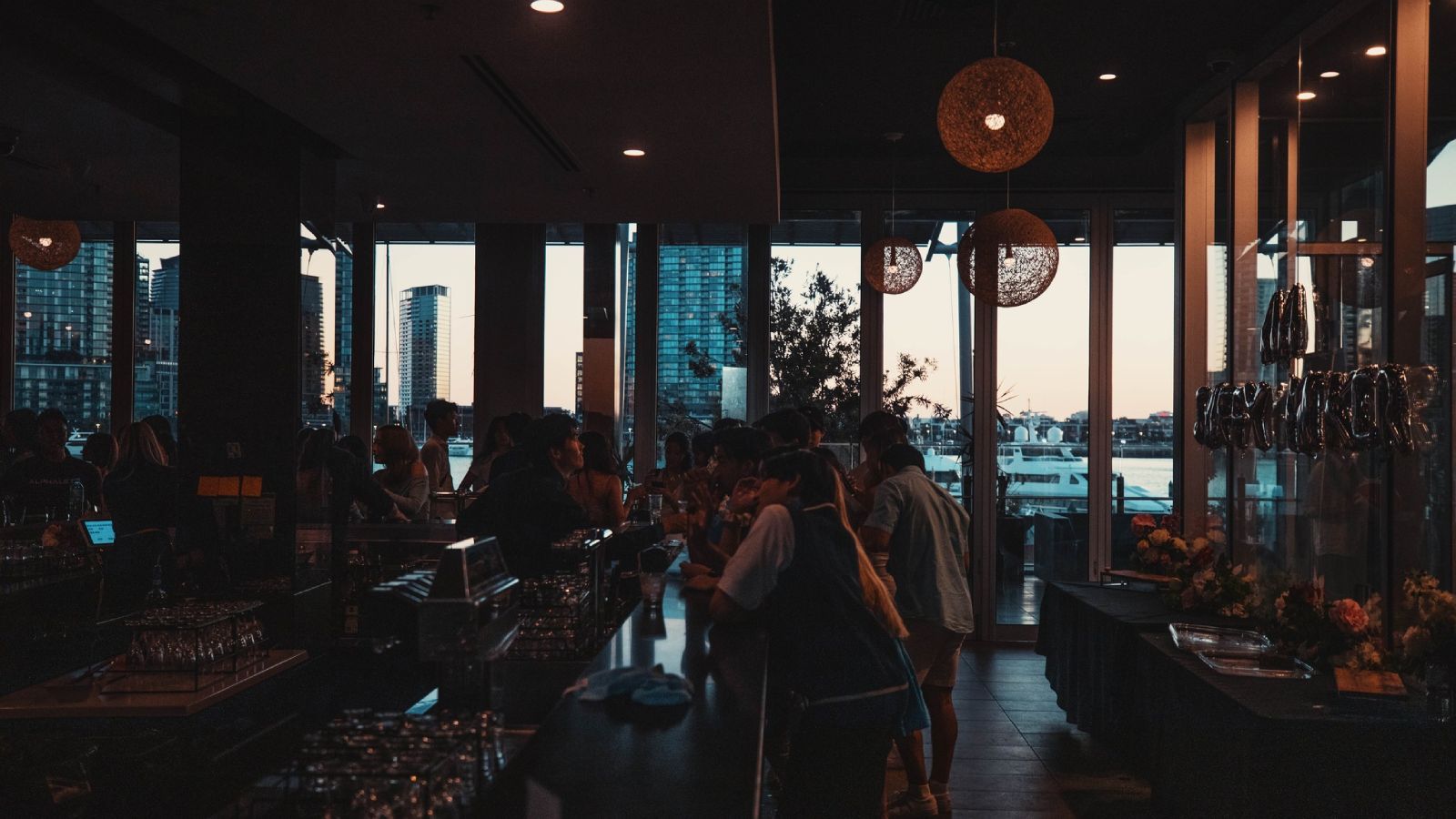 People enjoying drinks and conversation at a lively bar in The Promenade Docklands Waterfront Room.
