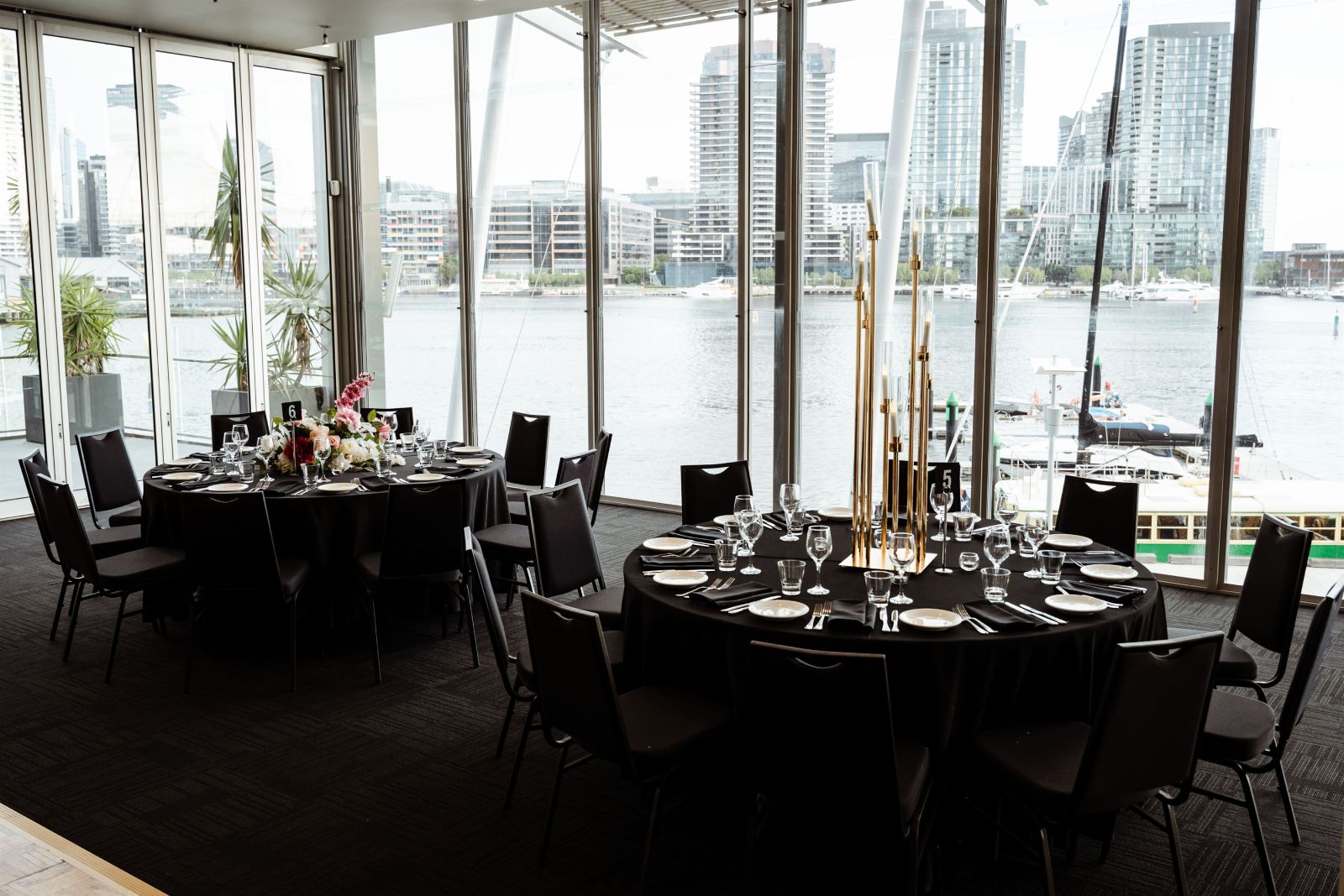 A beautifully decorated room at The Promenade Docklands, ready for a dinner party with tables and chairs set up.