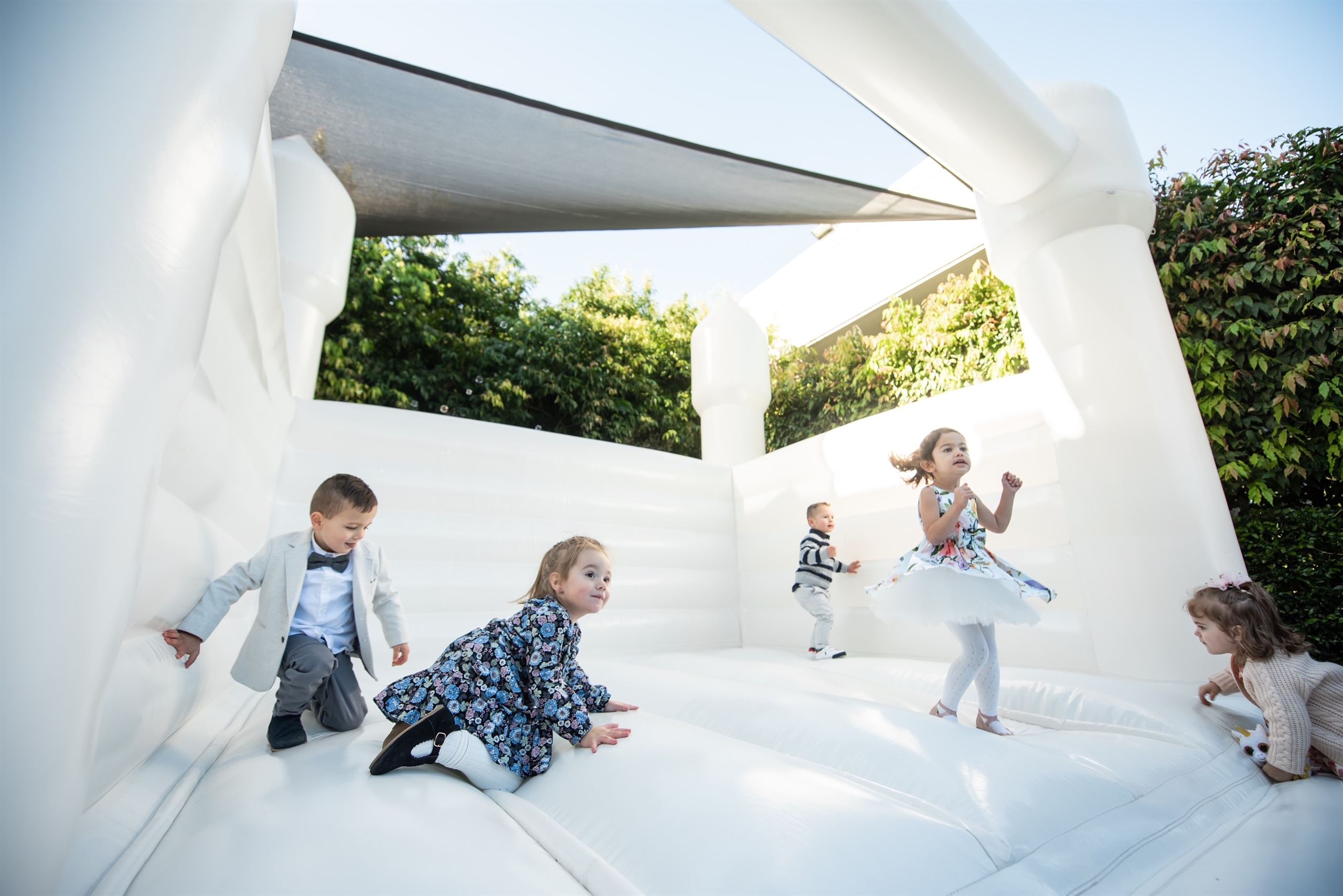 Children playing on an inflatable bouncy castle at a Christening venue in Melbourne, jumping with joy.