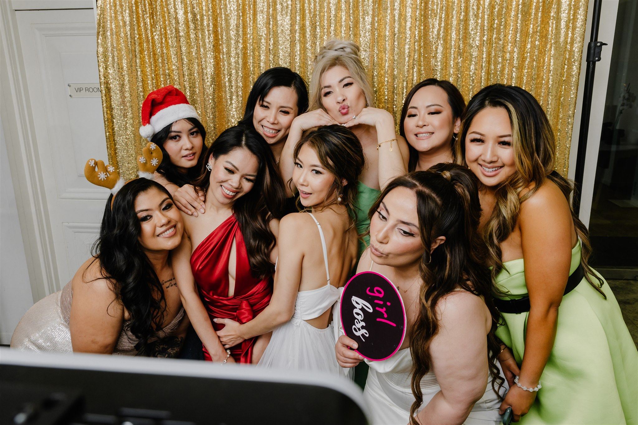 A group of women smiling and posing for a photo in front of a camera at a Christmas event in Melbourne.