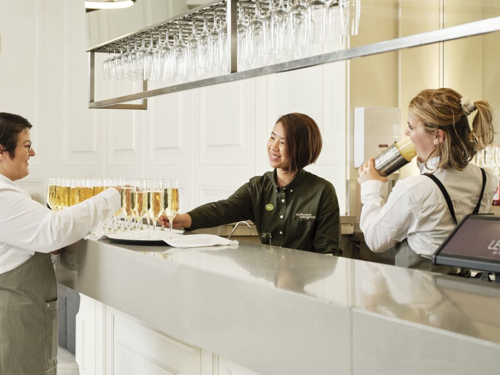 Bar staff serving flutes at a cocktail event in a Melbourne event space.