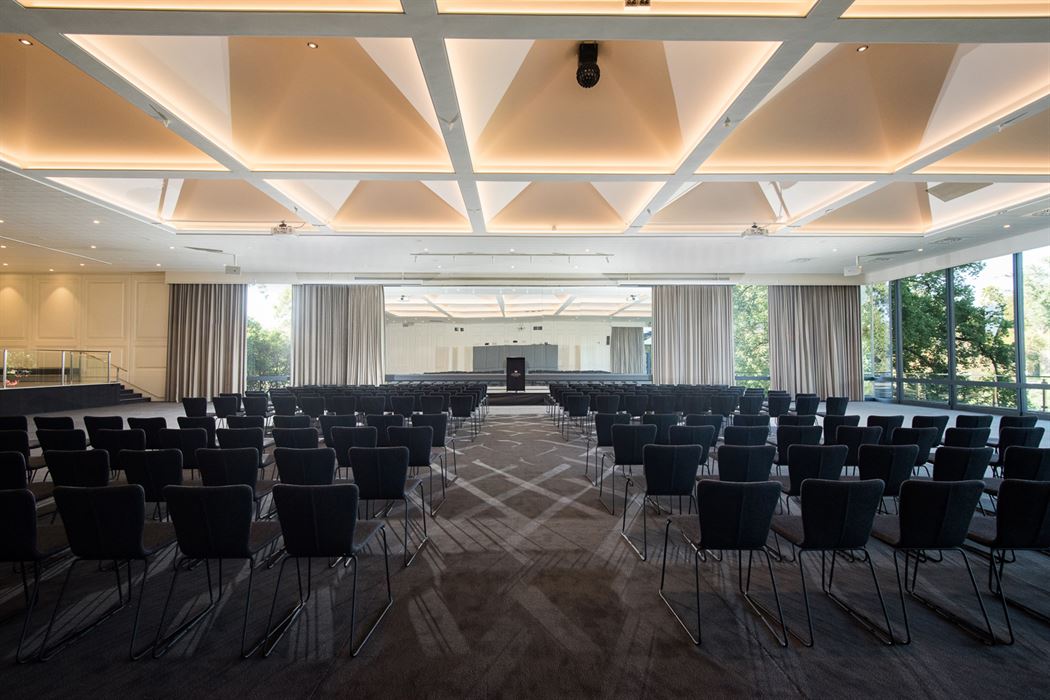 An expansive conference room designed for pharmaceutical events, featuring neatly arranged chairs and a ceiling adorned with bright lights.