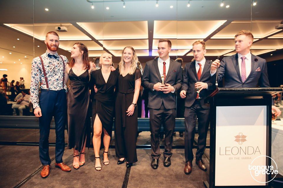 A group of people standing in front of a podium at a university ball venue in Melbourne.