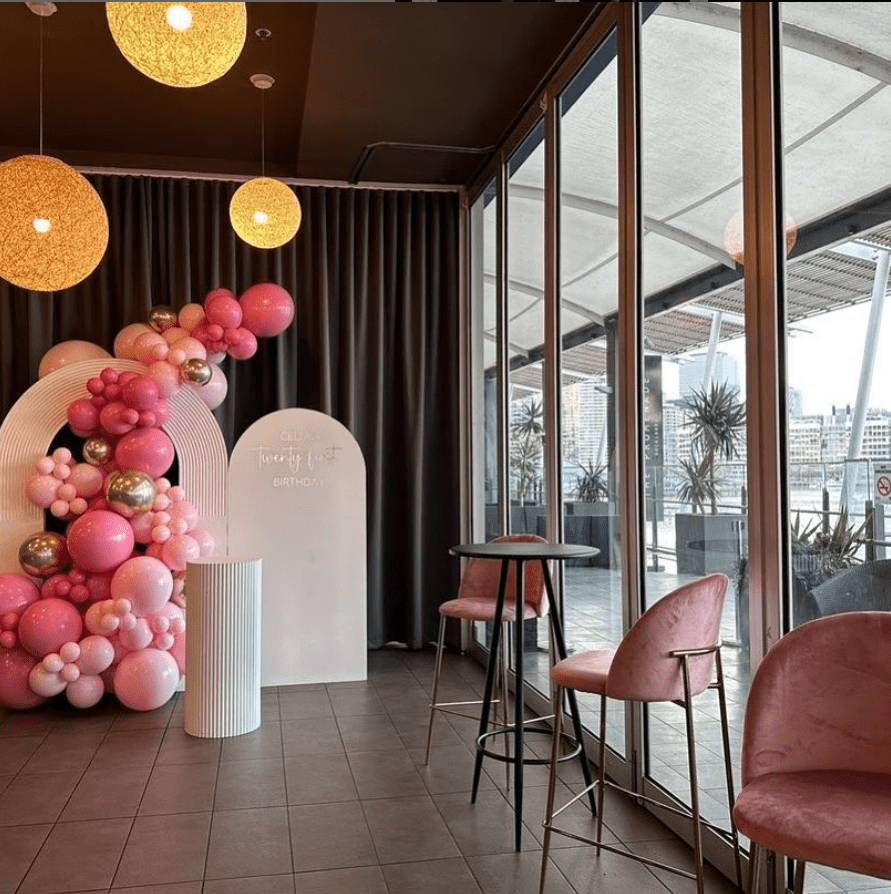 Pink balloon garland and white arch decorates an engagement party venue in Melbourne.